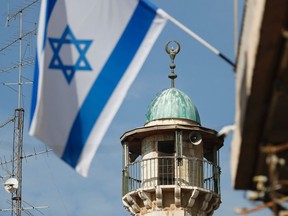 An Israeli flag waves in front of the minaret of a mosque in the Arab quarter of Jerusalem's Old City on November 14, 2016.