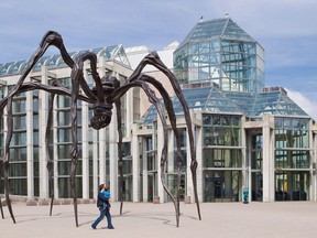 A man carries his young son underneath a spider sculpture entitled Maman in front of the National Gallery of Canada. Friday May 20, 2011.