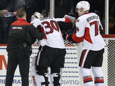 Ottawa Senators' goalie Andrew Hammond (30) is helped from the ice by Senators' defenseman Mark Borowiecki (74) and a team trainer during the first period of an NHL hockey game, Sunday, Dec. 18, 2016, in New York.