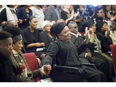 Bernadette Muzaliwa reaches across to hold her sister-in-law's hand during the service Saturday.