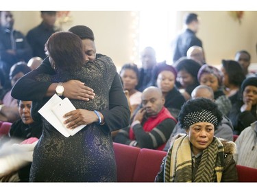 David Muzaliwa hugs a mourner at his sisters' funeral.