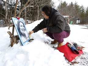Bridget Tolley places a photo of Kelly Morrisseau, who was murdered 10 years ago, at a memorial vigil in Gatineau Park on Saturday
