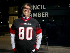 Calgary mayor Naheed Nenshi wears an obligatory smile while also wearing an Ottawa Redblacks jersey at City Hall in Calgar on  Dec. 5, 2016. He was making good on a bet with Ottawa Mayor Jim Watson in the wake of the Redblacks beating the Calgary Stampeders in the Grey Cup eight  days earlier.