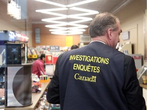 A Canada Revenue Agency officer in the Glebe Smoke Shop on Thursday.