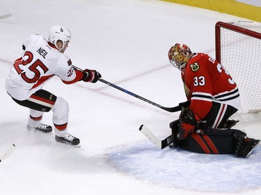 Chicago Blackhawks' Scott Darling (33) makes a save and keeps Ottawa Senators' Chris Neil from getting a rebound shot during the first period of an NHL hockey game, Tuesday, Dec. 20, 2016, in Chicago.