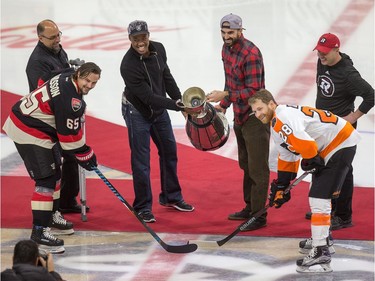 Henry Burris and Brad Sinopoli of the Ottawa Redblacks drop the puck from the Grey Cup for the ceremonial face off as the Ottawa Senators take on the Philadelphia Flyers in NHL action at Canadian Tire Centre. Taking the face-off are Erik Karlsson and Claude Giroux with Marcel Desjardins (L) and Rick Campbell (R) looking on.