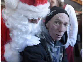 Noel Langlois gets a visit from Santa Claus during the 16th annual Christmas dinner at the Carleton Pub in Ottawa on Christmas Day,