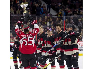Erik Karlsson shows off his team's trophy to the losing Chris Neil team following the skills competition.