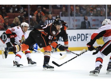 Mark Stone #61 and Mike Hoffman #68 of the Ottawa Senators defend against Rickard Rakell #67 of the Anaheim Ducks as he passes the puck during the first period of a game at Honda Center on December 11, 2016 in Anaheim, California.