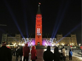 People watch a light show and a preview of Canada's 150th birthday celebration that will take place on the Hill Saturday night