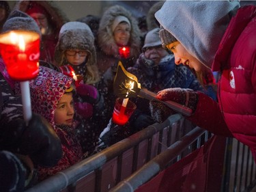 Olympic swimming gold medallist Penny Oleksiak lights a young girl's candle with her torch from the Fire of Friendship Relay.