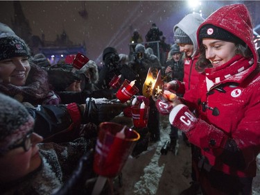 Paralympic swimmer Aurelie Rivard, right, and Olympic swimmer Penny Oleksiak light attendees' candles with their torches from the Fire of Friendship Relay.