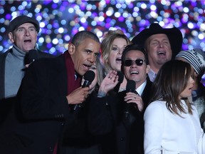 U.S. President Barack Obama sings Jingle Bells with Marc Anthony (C), James Taylor (L), Trisha Yearwood, Garth Brooks (R) and Eva Longoria (R, foreground) during the National Christmas Tree lighting ceremony, on December 1, 2016 in Washington, DC.