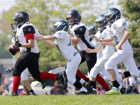 Rideau Redblacks slotback Cole Lalonde drags Nepean Eagles defensive back Owen Keenan down the field during mosquito action in the National Capital Amateur Football Association at Commonwealth Field on Monday September 7, 2015.