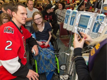 Sarah Telford, 18, gets a photo with Dion Phaneuf as the Ottawa Senators make their annual Christmas visit to CHEO and visit with some of the children and staff. They also brought gifts including a DSLR camera, video games, movies, blankets and plush Sparty dolls for CHEO's use in its effort to enhance the lives of hospital patients.