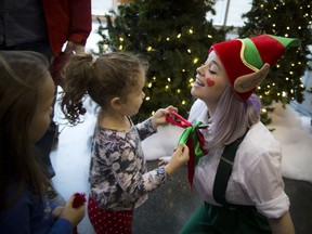 Three-year-old Emma Graham fixes up an elf's tie during the 16th annual Mayor's Christmas Celebration at city hall on Saturday, Dec. 3, 2016.