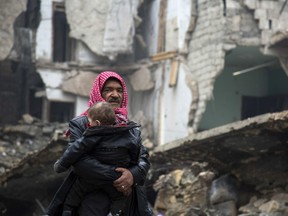 TOPSHOT - Syrians leave a rebel-held area of Aleppo towards the government-held side on December 13, 2016 during an operation by Syrian government forces to retake the embattled city.