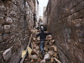 TOPSHOT - A Syrian boy makes his way through the rubble of destroyed buildings as he heads to his house in Aleppo's Dahret Awad neighbourhood on December 17, 2016, after pro-government forces retook the area from rebel fighters. /