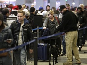 A member of Homeland Security walks with his K-9 dog as travellers wait in the TSA security line at O'Hare International Airport on Dec. 23, 2016 in Chicago.