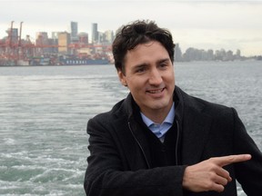 The city of vancouver is shown in the background as Prime Minister Justin Trudeau tours a tugboat in Vancouver Harbour, Tuesday, Dec.20, 2016.