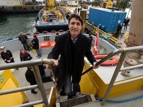 Prime Minister Justin Trudeau climbs a set of stairs as he tours a tugboat in Vancouver Harbour.