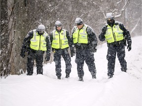 Police trudge through the snow in the McCarthy Road area seeking possible evidence from a double homicide Friday night.