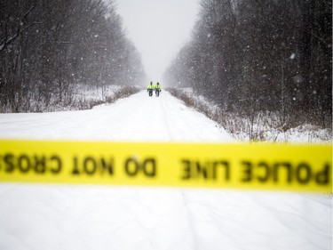 Members of Ottawa Police's Emergency Services Unit walk down the train line that crosses McCarthy Road looking for evidence from the double-homicide of sisters Nasiba and Asma A-Noor.