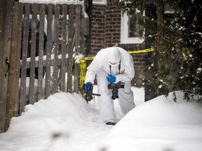 A member of the Ottawa Police's Forensic Identification Section ducks under police tape Saturday morning.