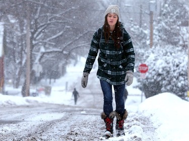 With sidewalks still piled with snow Fiona McNeill walks on the roads en route to school at the University of Ottawa in the Sandy Hill area. Snowploughs were out in full force following 16 centimetres of snow by Monday (Dec. 12, 2016) at noon, slowing the roads and early-morning commute.