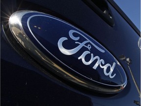 FILE - This Oct. 25, 2011, file photo, shows a Ford logo,on the tailgate of a pick-up truck, and on a Ford dealership sign at Salem Ford in Salem, N.H. This holiday seasons blitz of college football bowl games will feature a reshuffled roster of corporate sponsors spending millions to thrust their names in front of fans watching on TV and in the stands. The Ford Motor Quick Lane Bowl is making its debut this season. (AP Photo/Charles Krupa, File)