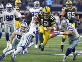 Green Bay Packers quarterback Aaron Rodgers (12) rushes for a gain as Dallas Cowboys&#039; Sean Lee (50) and Anthony Brown (30) defend during the second half of an NFL divisional playoff football game Sunday, Jan. 15, 2017, in Arlington, Texas.