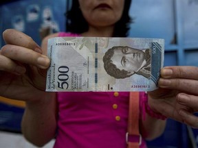 A bank customer shows a new bank note of 500 Bolivars outside a bank in Caracas, Venezuela, Monday, Jan. 16, 2017. As the nation experiences triple-digit inflation, the government rolled out larger denomination bank notes on Monday, ranging in value from 500 to 20,000 bolivars. (AP Photo/Fernando Llano)