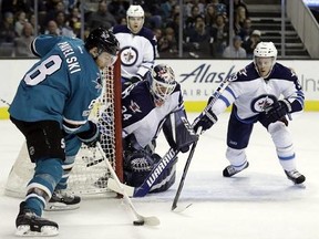 San Jose Sharks' Joe Pavelski (8) controls the puck in front of Winnipeg Jets goalie Michael Hutchinson (34) and Toby Enstrom, right, during the second period of an NHL hockey game, Monday, Jan. 16, 2017, in San Jose, Calif.