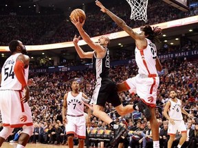 San Antonio Spurs guard Manu Ginobili (20) scores on a reverse lay-up over Toronto Raptors centre Lucas Nogueira (92) as guard Kyle Lowry (7) forward Patrick Patterson (54) and guard Cory Joseph (6) look on during first half NBA basketball action in Toronto on Tuesday, January 24, 2017.