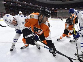 Philadelphia Flyers' Sean Couturier (14) plays the puck against the boards past Toronto Maple Leafs&#039; Martin Marincin (52) and Frederik Gauthier (33) during the second period of an NHL hockey game, Thursday, Jan. 26, 2017, in Philadelphia.