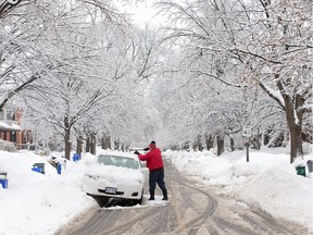 A man cleans off his car parked on Powell Ave in the Glebe as the region was blanketed with a fresh batch of snow overnight Sunday.