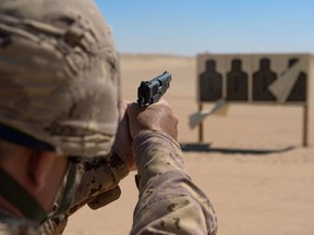 A member of the Area Security Force practices firing the Browning 9mm pistol from the kneeling position at the weapons range during Operation IMPACT on March 4, 2015. Photo: OP Impact, DND