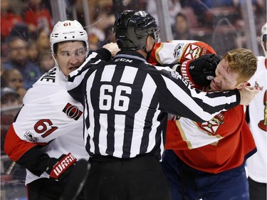 Ottawa Senators right wing Mark Stone (61) and Florida Panthers defenseman Michael Matheson fight as linesman Darren Gibbs separates them during the first period of an NHL hockey game, Tuesday, Jan. 31, 2017, in Sunrise, Fla.