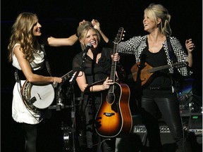 FILE - In this Oct. 18, 2007 file photo, Emily Robison, left, and Martie Maguire, right, adjust Natalie Maines' hair as the Dixie Chicks perform at the new Nokia Theatre in Los Angeles.