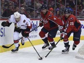 Ottawa Senators right wing  Casey Bailey (37) fights for the puck with Washington Capitals defenseman Taylor Chorney (4) and center Lars Eller (20), of Denmark, during first period of an NHL hockey game, Sunday, Jan. 1, 2017, in Washington.