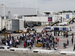 People stand on the tarmac at the Fort Lauderdale-Hollywood International Airport after a shooter opened fire inside a terminal of the airport, killing several people and wounding others before being taken into custody, Friday, Jan. 6, 2017, in Fort Lauderdale, Fla.