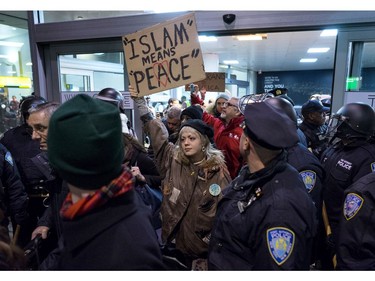 Protesters are surrounded by police officers and travellers as they pass through an exit of Terminal 4 at John F. Kennedy International Airport in New York.