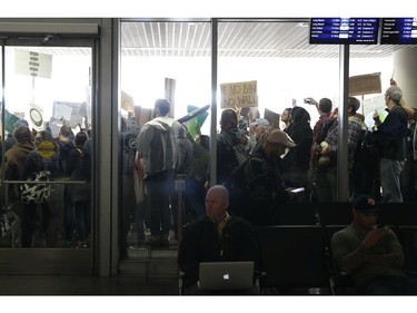 People at the international arrival terminal as demonstrators hold signs against a ban on Muslim immigration at San Francisco International Airport.