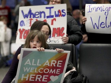 Rachel Walker, centre, of St. Paul and her daughter, Evelyn, 7, front, join others in protesting an executive order signed by U.S. President Donald Trump restricting immigration from several Muslim nations Saturday, Jan. 28, 2017, at the Minneapolis-St. Paul International Airport.