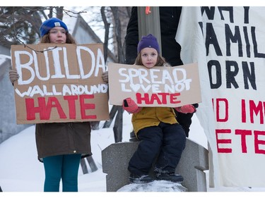 Ronan, 11, and Seneca, 5, Chassin hold up their signs as an anti President Trump protest takes place at the Embassy of the United States in Ottawa.