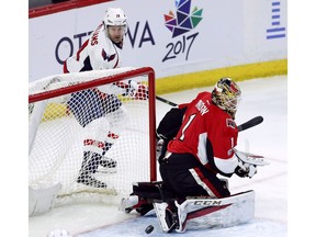 Ottawa Senators goalie Mike Condon looks back at the puck as the Washington Capitals' Justin Williams attempts a wraparound shot.