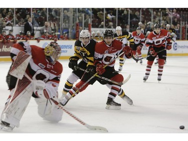 Ottawa 67's goalie Leo Lazarev handles a puck way out of his crease as teammate Peter Stratis and the Kingston Frontenacs' Cal Davis charge into the play.