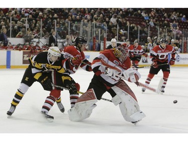 Ottawa 67's goalie Leo Lazarev handles a puck way out of his crease as teammate Peter Stratis and Kingston's Cal Davis charge into the play.