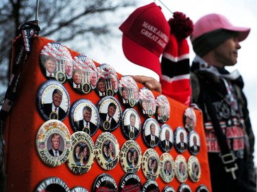 A man waits for customers with his merchandises featuring pictures of US President-elect Donald Trump near the capitol building in Washington, DC, on January 19, 2017, where final preparations were underway a day ahead of the inauguration of the 45th US president.