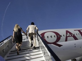 FILE - In this Nov. 14, 2011 file photo, visitors walk up stairs to inspect a Boeing 777-200LR aircraft in Qatar Airways livery at the Dubai Airshow in Dubai, United Arab Emirates. Qatar Airways has launched the world&#039;s longest scheduled commercial airline route with the arrival of its flight from Doha to Aukland, New Zealand. The Gulf carrier said flight QR920 touched down in Aukland early on Monday, Feb. 6, 2017, after covering a distance of 14,535 kilometers (9,032 miles). (AP Photo/Kamran Je